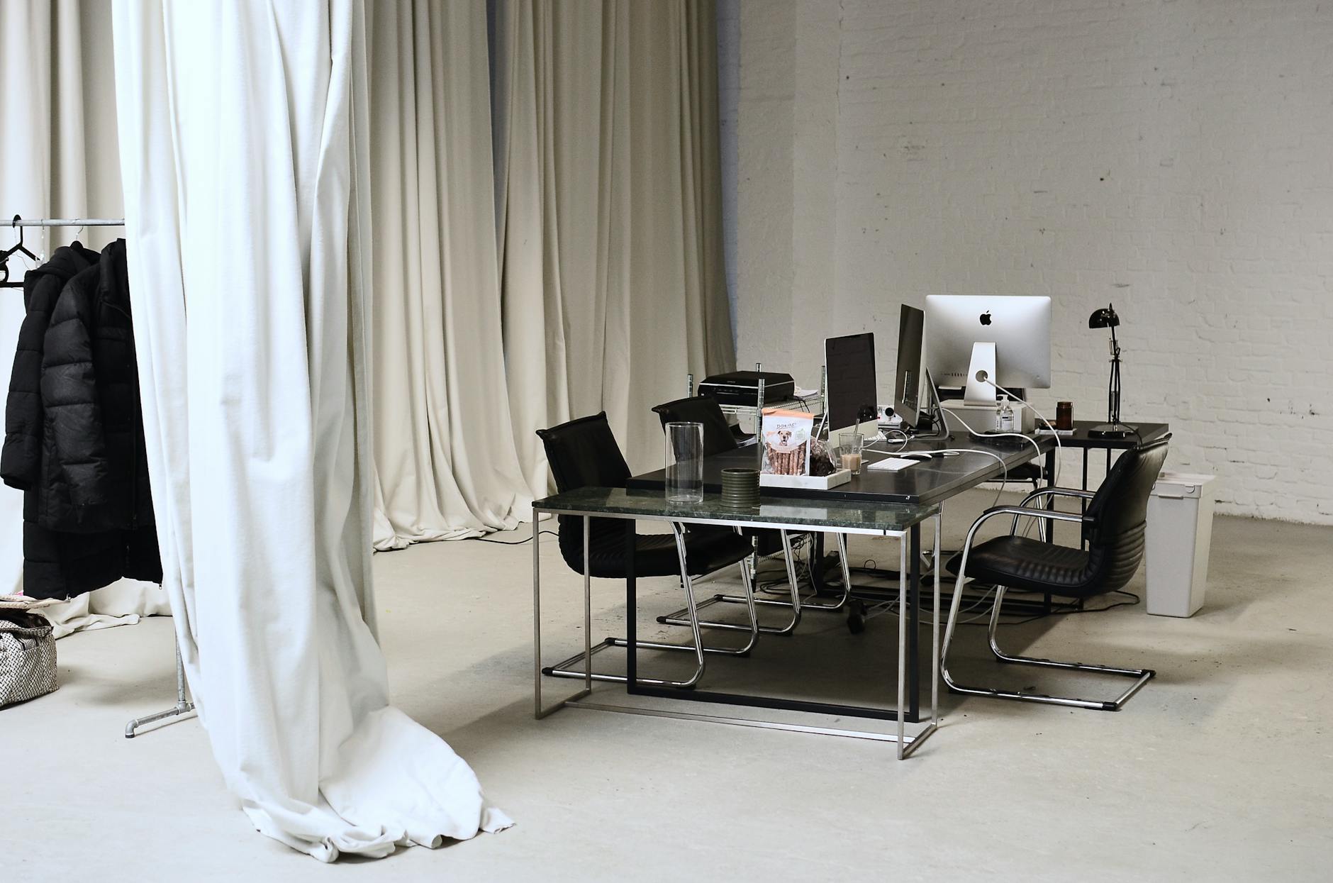 Interior of conference room with modern personal computers placed on table with clothes hanging on rail